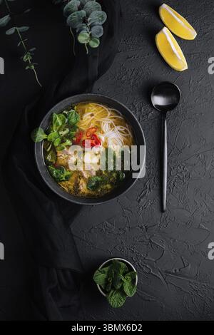 food still-life, Chicken soup with vegetables in black bowl with red pepper Stock Photo