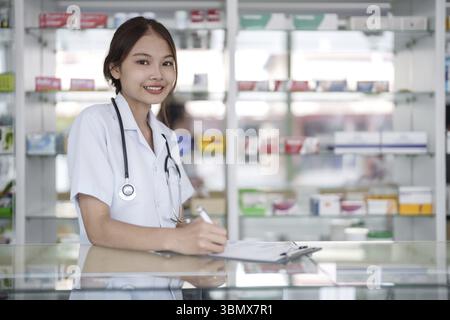 Portrait of asian pharmacist working in pharmacy with medication at pharmacy counter Stock Photo