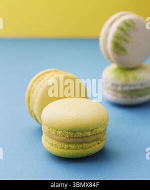 food still-life, Sweet and colorful macaroons on blue with yellow background Stock Photo