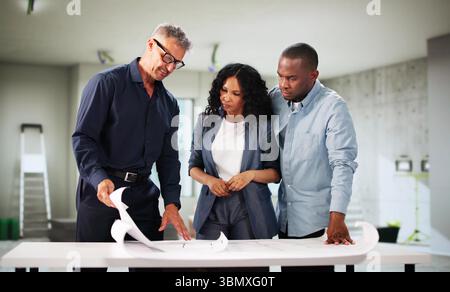 Young Black Couple Discussing House Renovation With Interior Designer. Stock Photo