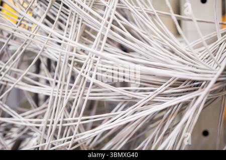 Showing tangled white network cables crossing flat design rack patch panel with metal guides Stock Photo