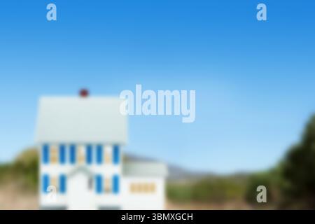 Miniature house model is standing in 3D render on dirt field with rolling hills blurred background Stock Photo
