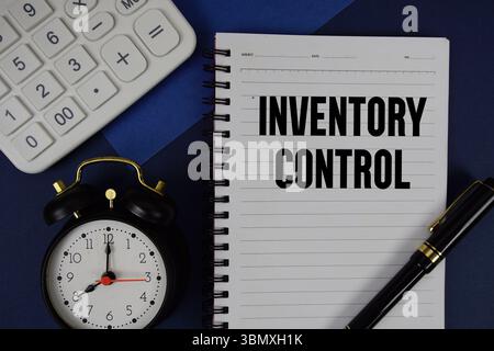Inventory Control text written on notepad with calculator and alarm clock on navy blue background Stock Photo