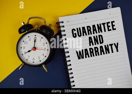 Guarantee And Warranty text written on notepad with alarm clock on blue background Stock Photo