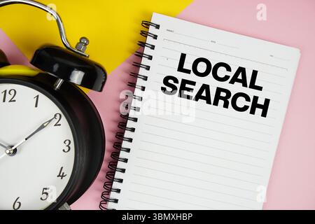 Local Search text written on notepad with alarm clock on pink background Stock Photo