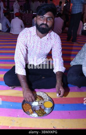 Indian man eating food at wedding function in traditional attire Stock Photo