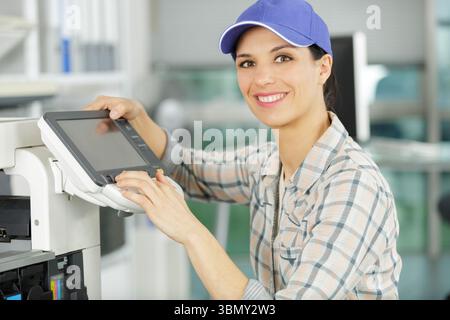 happy woman smiling at the camera fixing a printer Stock Photo