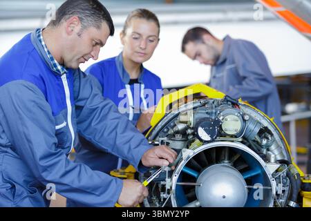 aero engineer and apprentice working on helicopter in hangar Stock Photo