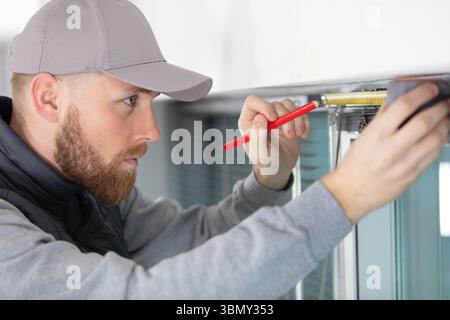 man measuring window prior to installation Stock Photo