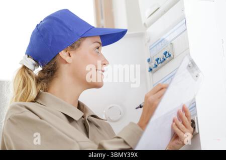 happy female worker inspecting fuse board Stock Photo