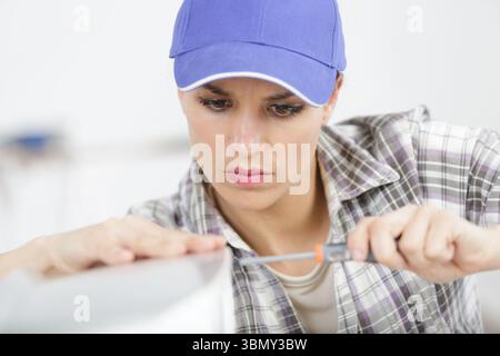 happy female builder with screwdriver fixing electric device Stock Photo