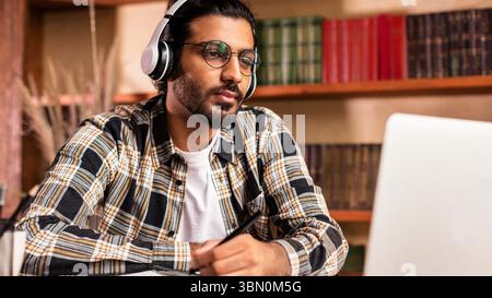 Arab Student Guy Learning Online At Laptop Sitting In Library Stock Photo
