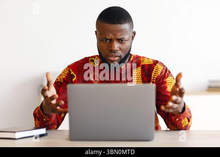 Computer Problems. Frustrated African Businessman In Traditional Clothes Having Troubles With Computer Stock Photo