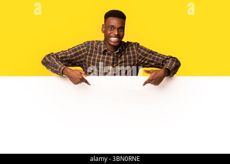 Free Place For Ad. Cheeful Black Guy Pointing Down At White Board Stock Photo