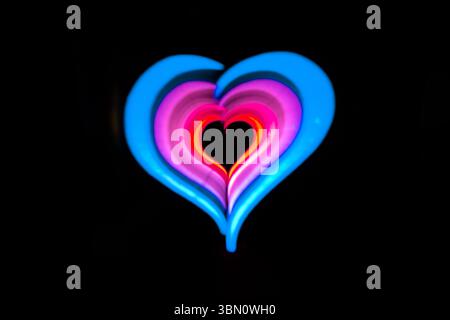 Multi color heart shape outline, light painting photography, long exposure, against a black background Stock Photo