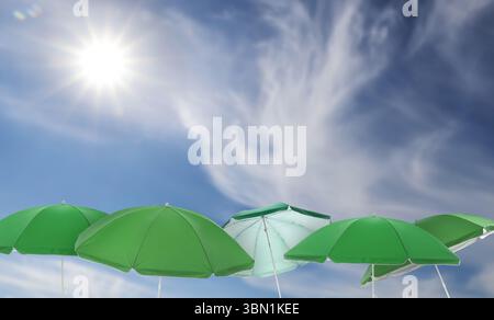 Green beach umbrellas against blue sky on sunny day Stock Photo
