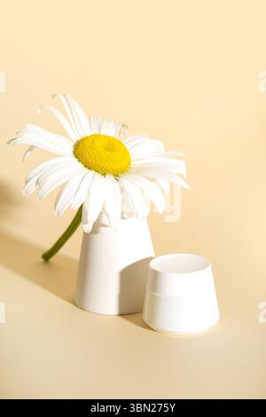 Composition with jar of cosmetic product, chamomile flower and plaster podium on color background Stock Photo