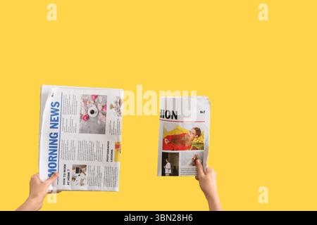 Women with newspapers on yellow background Stock Photo