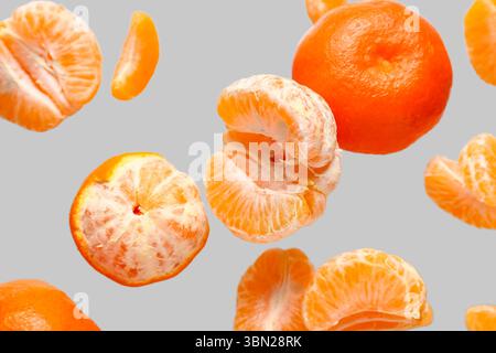 Flying sweet ripe mandarins on grey background Stock Photo