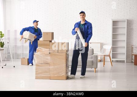 Male workers wrapping cardboard boxes with stretch film in room Stock Photo