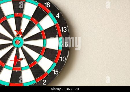 Board with darts hanging on light wall Stock Photo