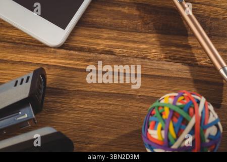 Rubber band ball with stapler on wooden table Stock Photo