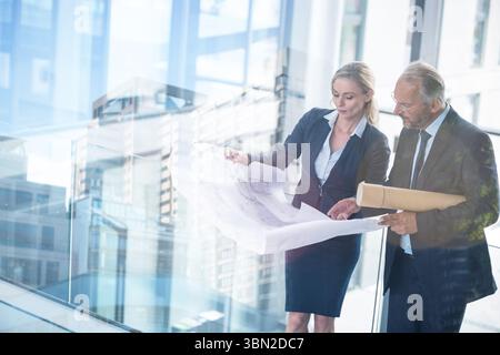Business people discussing over blueprint in office Stock Photo