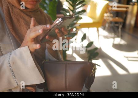 Woman using smartphone in bright cafe setting Stock Photo