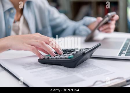 Close-up of hands working on financial documents with a calculator. Useful for finance, tax, budget, accountant, audit, and business planning concepts Stock Photo