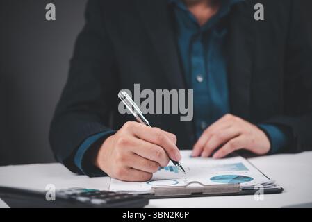 Businessman analyzing financial report with pen, reviewing charts and data. Ideal for finance, business strategy, accounting, planning, and data analy Stock Photo