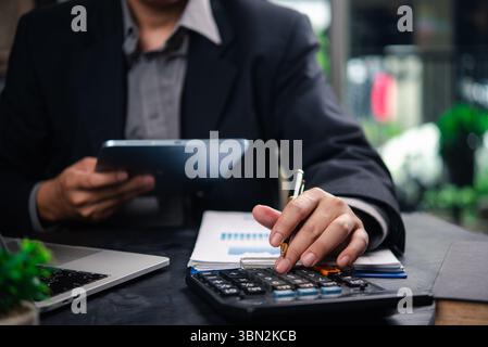 Businessman accountant reviewing financial documents and using a tablet and calculator to plan business strategies and data analysis. Stock Photo