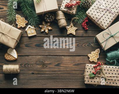 Christmas background with place for text. Gifts, fir branches and gingerbread cookies on a wooden background form a frame Stock Photo