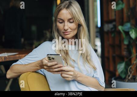 Young attractive blonde woman uses mobile phone to surf the internet Stock Photo