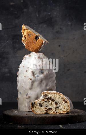 Christmas bread - stollen with nuts and dried fruits on a wooden board, balancing food, dark photo Stock Photo