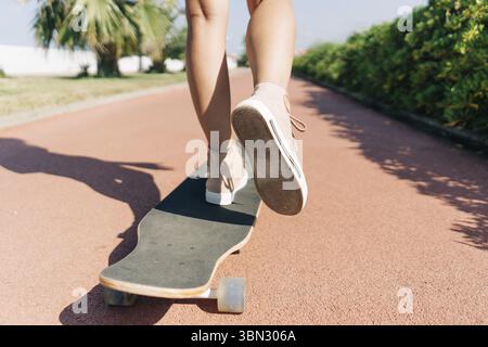 Close-up of female legs on a skateboard, one leg is repelled from the surface. Outdoor workout and hobby Stock Photo