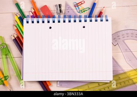 Flat design showing notebook on wooden desk surrounded by pencils, rulers, compass, copy space Stock Photo
