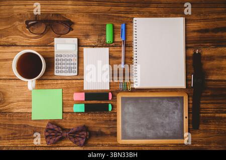 Flat-lay scene showing coffee cup, glasses, calculator, notepad, pen, highlighters on wood table Stock Photo