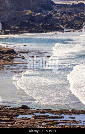 Breaking waves on the beach by a rocky coast Stock Photo