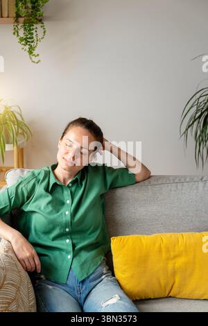 Young adult woman resting comfortably on sofa indoors Stock Photo