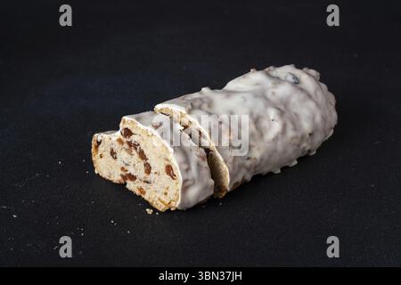 Slices of fruit bread in white glaze on a dark background, dessert Stock Photo