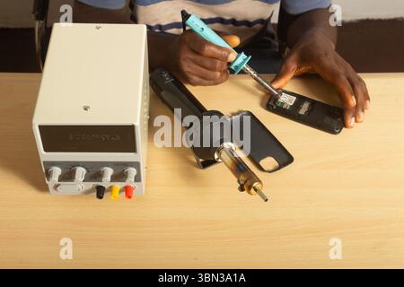 closeup technician hands  soldering phone repair heat gun digital dc power supply unit tabletop small business work from home entrepreneur Stock Photo