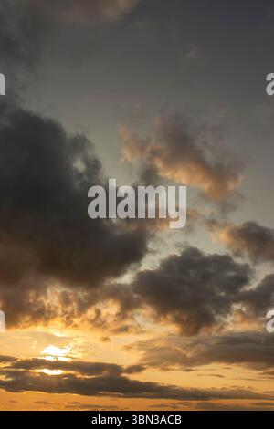 Cloudy sunset background backdrop with the sun rays breaking through the clouds. Stock Photo