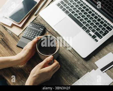 Coffeebreak at the workplace in the office. Unrecognizable woman holding a mug of coffee Stock Photo
