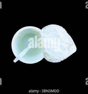 it is empty yoghurt cup with spoon isolated on black. Stock Photo