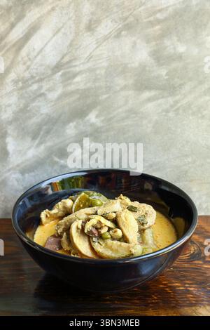 it is green curry with chicken on wooden table and cement background. Stock Photo
