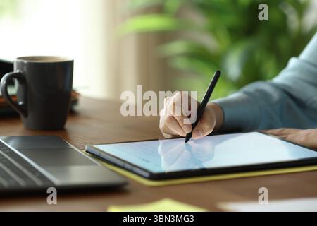 Close up portrait of office worker hands using stylus pen to handwrite on tablet on a wooden table Stock Photo