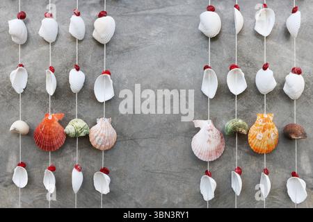 it is hanging seashells mobile on concrete wall for design. Stock Photo