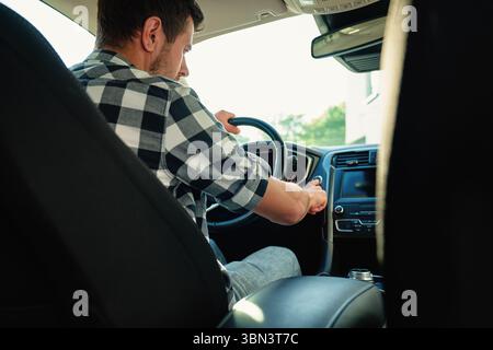 Man sitting in car and pressing engine start button. Starting vehicle using modern ignition technology. Person ready to driving car Stock Photo