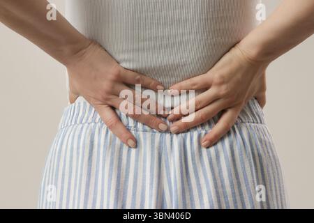 Young woman suffering from back or kidney pain, studio photography Stock Photo