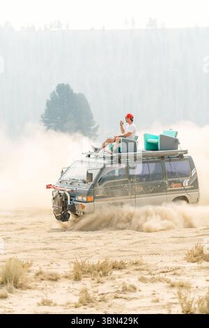 Adventurer enjoying scenic ride on off-road van in desert landscape Stock Photo